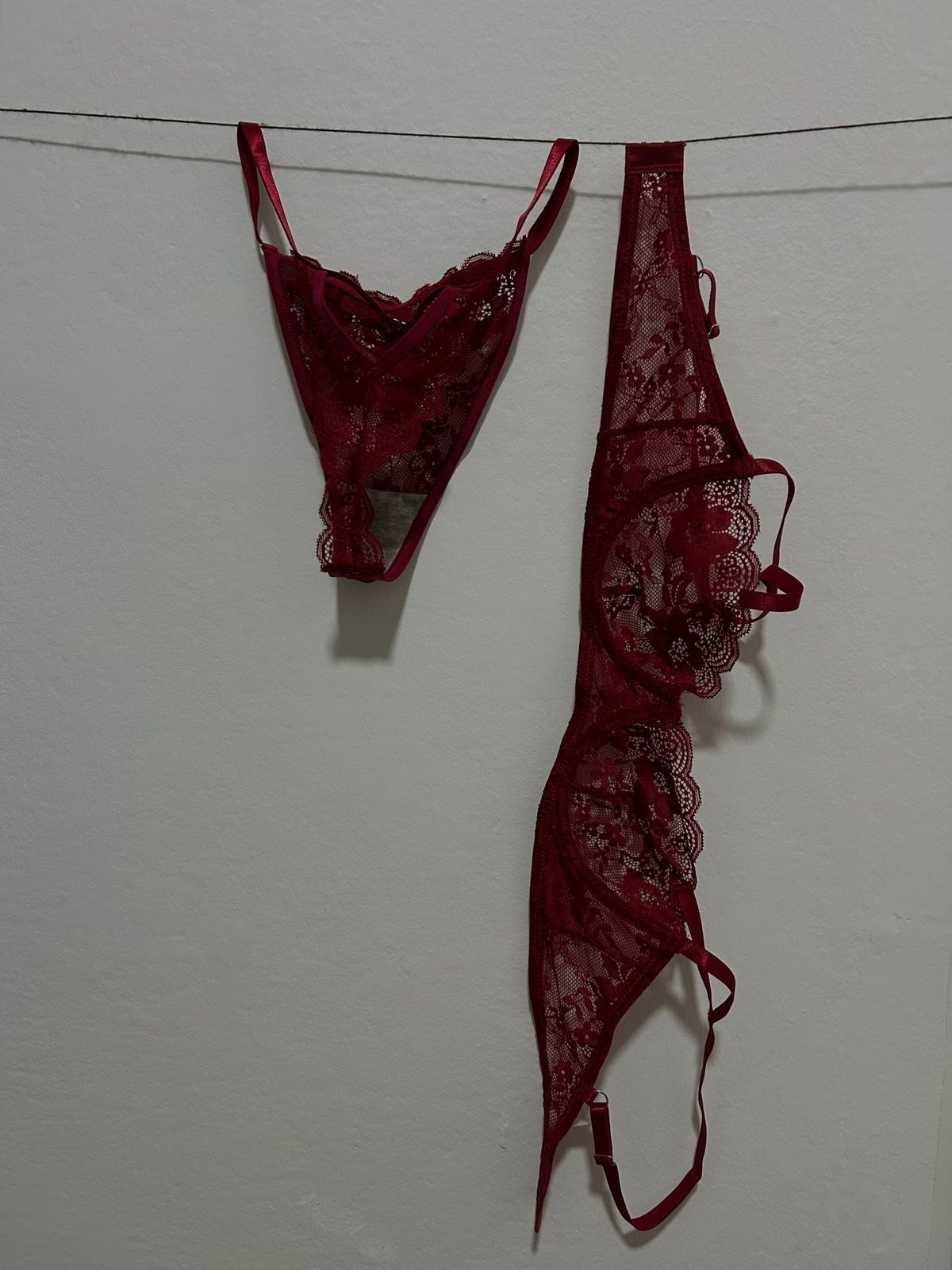 services-img Delicate red lace lingerie pieces featuring sheer mesh and floral lace patterns are hanging on a thin line against a light wall. The composition highlights the intricate texture of the lace and creates a romantic, intimate, and elegant atmosphere.