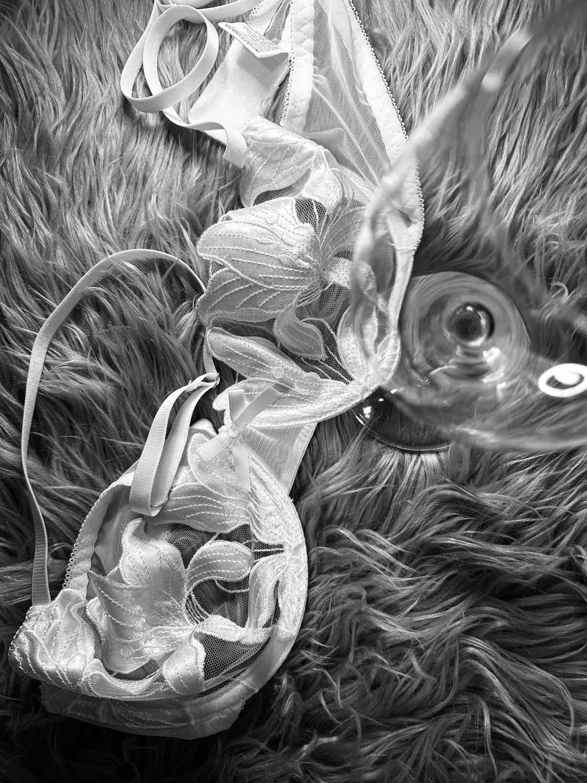 Crafting Captivating Headlines: Your awesome post title goes here A delicate white lace bra featuring sheer mesh panels and intricate floral embroidery, arranged on a soft faux-fur background. A wine glass placed beside the lingerie adds a sensual and elegant atmosphere, highlighting the refined, feminine, and intimate aesthetic of the piece.